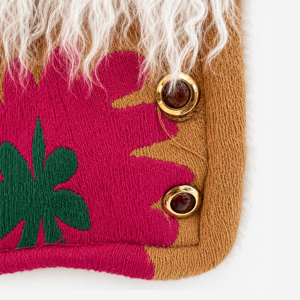 Close-up detail of the Coco Afghan Jacket No. 6, showing the magenta and green flower embroidery, gold button closure, and cream shearling trim.