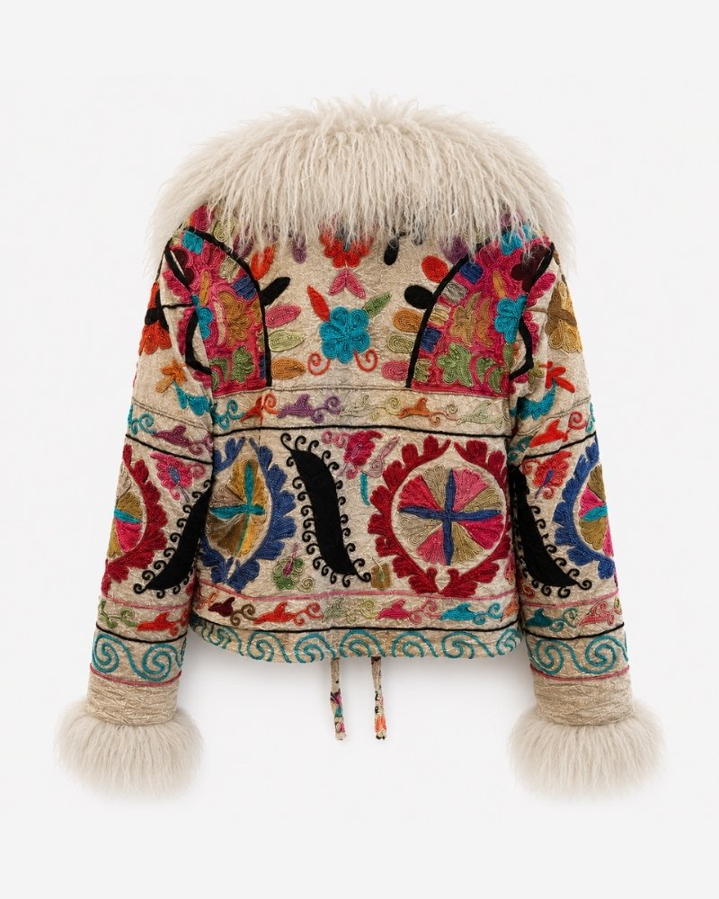 The Martina Coat No. 9, back view, in tan with dense multicolour embroidery featuring black paisley scrolls, red and blue sun medallions, a teal wave border, and a cream shearling collar and cuffs.