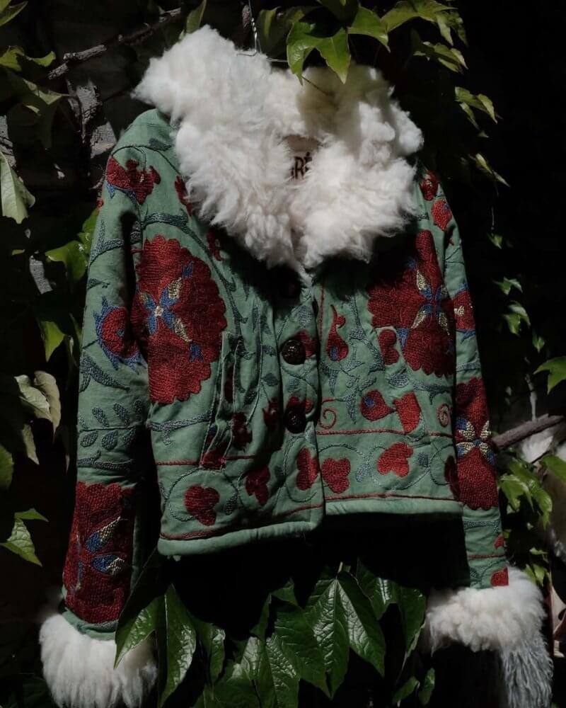 The Afghan Coat Coco No. 2 by Lunaré – styled outdoor shot, green coat with red floral embroidery and cream shaggy shearling collar and cuffs.