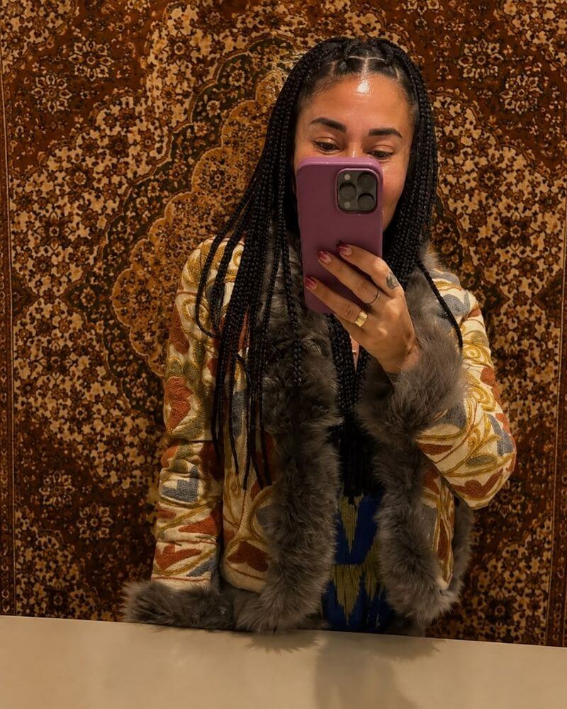 The Afghan Coat Eliza by Lunaré – lifestyle mirror shot on model, gold and rust patterned coat with grey shaggy shearling trim.