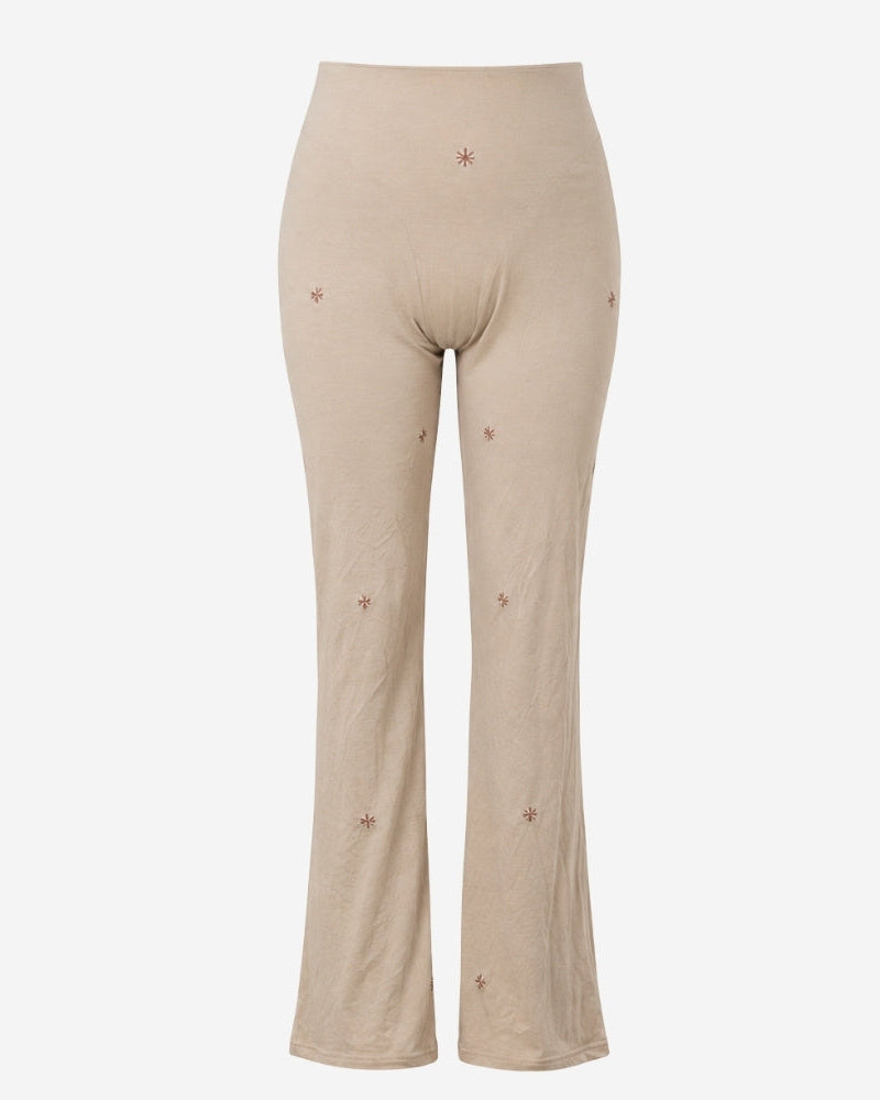 Estrania pants by Lunaré – high-waisted flared trousers in cream with hand-embroidered rust star motifs, 100% cotton.
