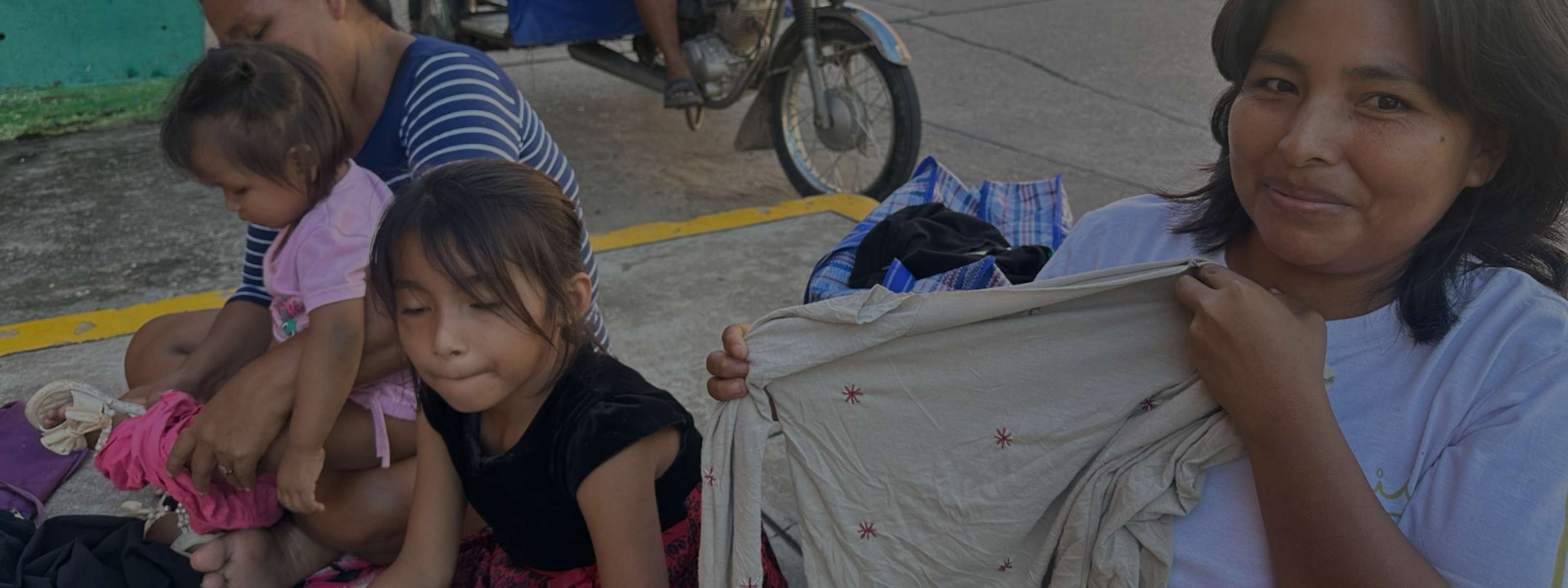 Lunaré production – artisan in Peru holding an embroidered garment with children nearby.