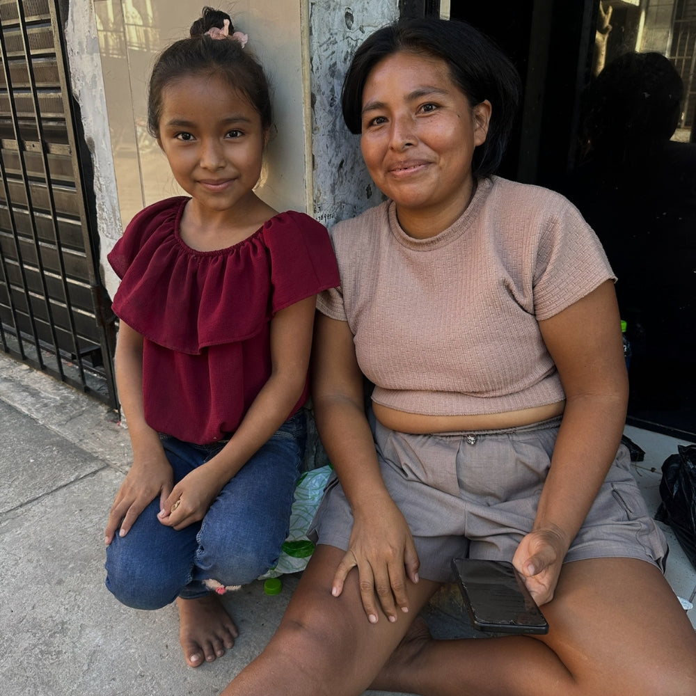 A mother and young daughter sitting together on a doorstep, smiling, part of Lunaré's behind-the-scenes production photos.