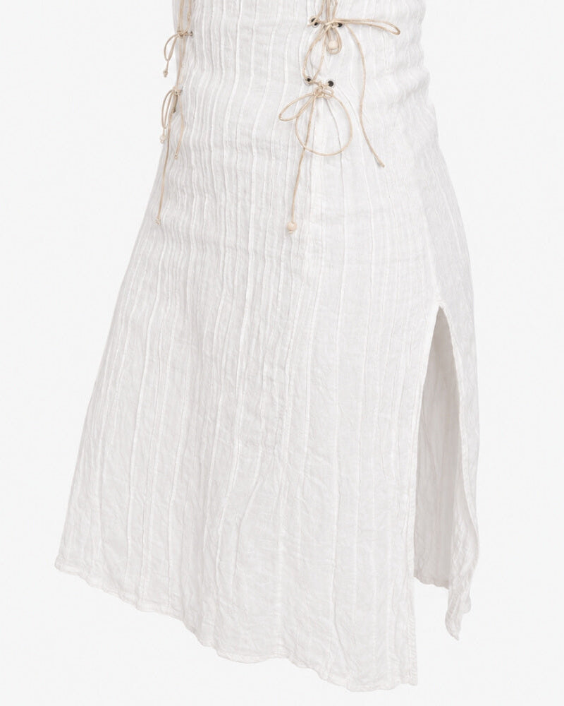 Detail view of the Rose Dress in white, showing the high slit and adjustable lacing with pearl detail.