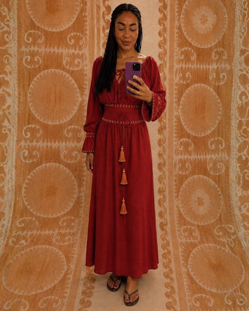 Sanaya Kim Dress by Lunaré – mirror selfie on model, rust red maxi dress with long sleeves and tasseled waist tie.