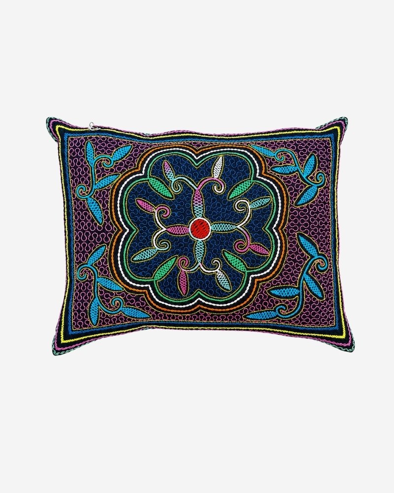 Hand-Embroidered Shipibo Cushion No. 11 in plum, with a scalloped navy flower medallion at its centre and teal leaf branches extending to the corners.
