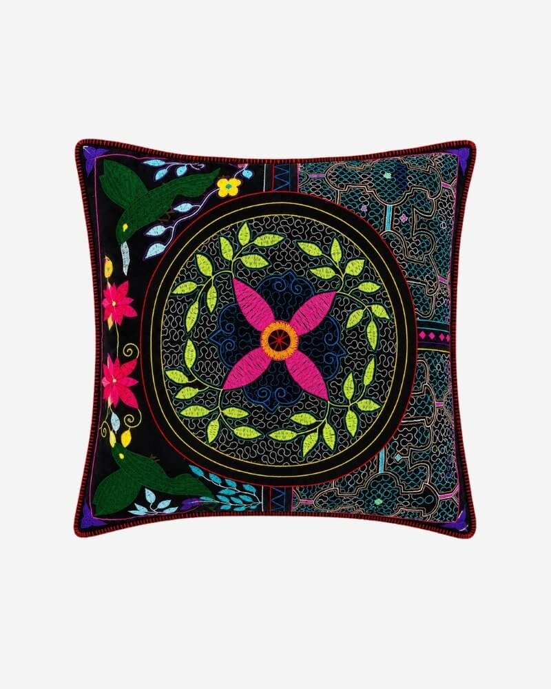 Hand-Embroidered Shipibo Cushion No. 15 in navy, with a large pink flower medallion encircled by a green vine wreath and embroidered ferns in the corners.