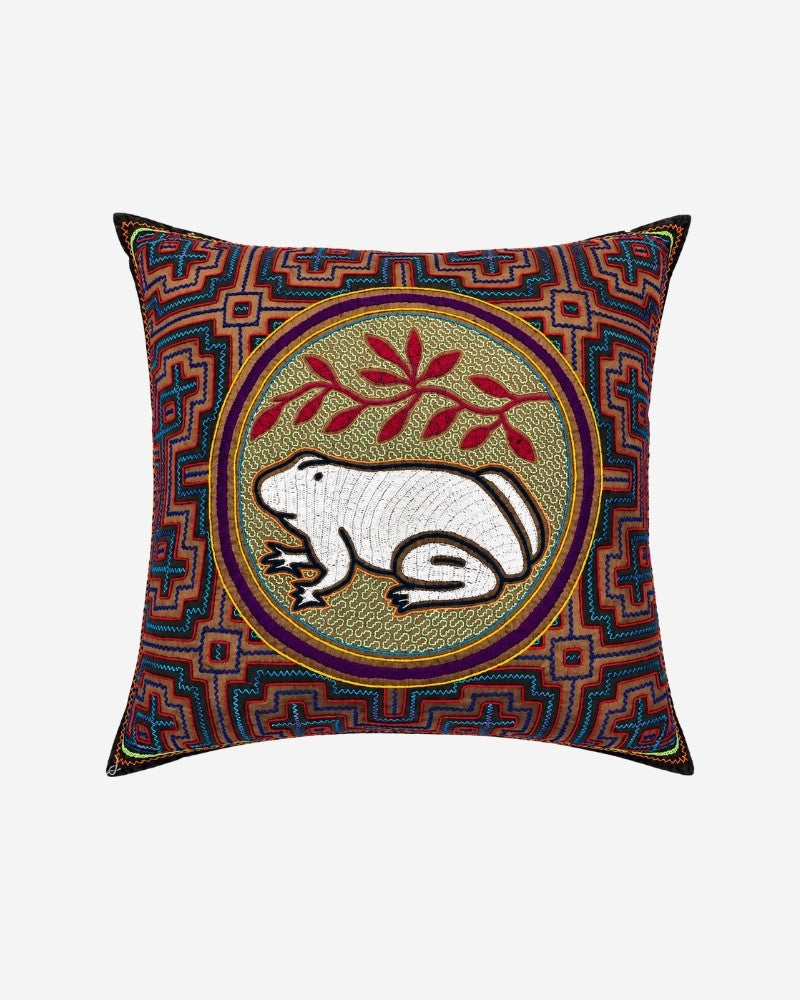 Hand-Embroidered Shipibo Cushion No. 3 with a white frog and leaf motif at its center, framed by a traditional Kené-inspired geometric pattern.
