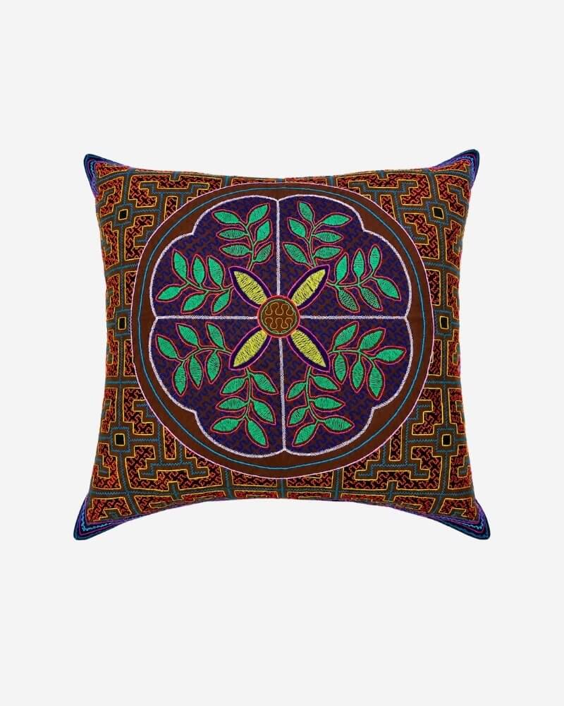 Hand-Embroidered Shipibo Cushion No. 2 in rust with a central floral medallion in green and gold, framed by a geometric border.