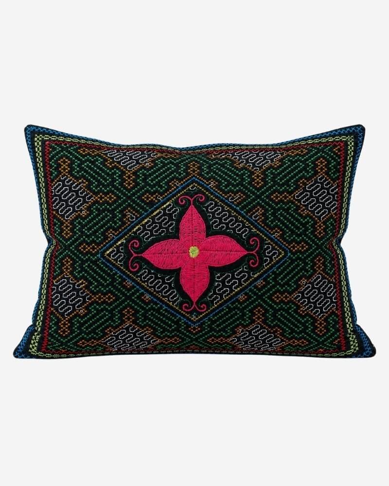 Hand-Embroidered Shipibo Cushion No. 7 in green, with a diamond-shaped geometric maze border and a central pink four-petal flower motif with a yellow centre.