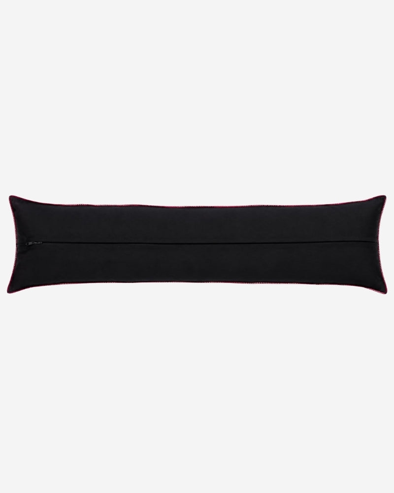 Hand-Embroidered Shipibo Cushion No. 17 by Lunaré – back view, long bolster shape, solid black cotton cover with pink contrast piping.