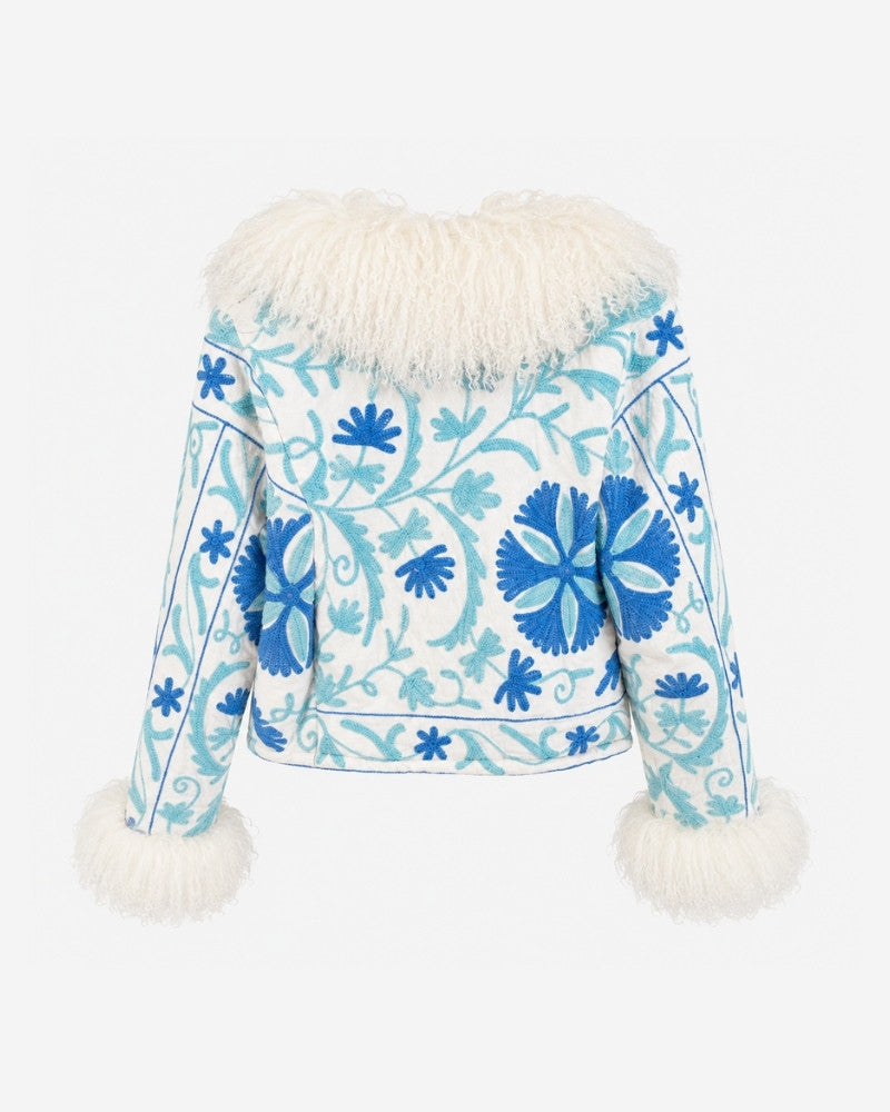 The Afghan Coat Martina No. 8 by Lunaré – back view, cream jacket with hand-embroidered blue floral stitching and a voluminous Tibetan lamb fur collar and cuffs.