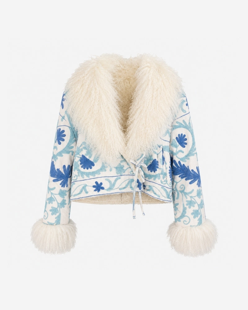 The Afghan Coat Martina No. 8 by Lunaré – cream jacket with hand-embroidered blue floral stitching and a voluminous Tibetan lamb fur collar and cuffs, front view.