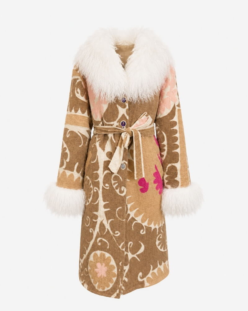 The Afghan Coat Silje by Lunaré – front view, long mid-calf coat in tan with cream hand-embroidered swirl pattern, pink floral accent, cream shaggy shearling collar and cuffs, and tie belt.