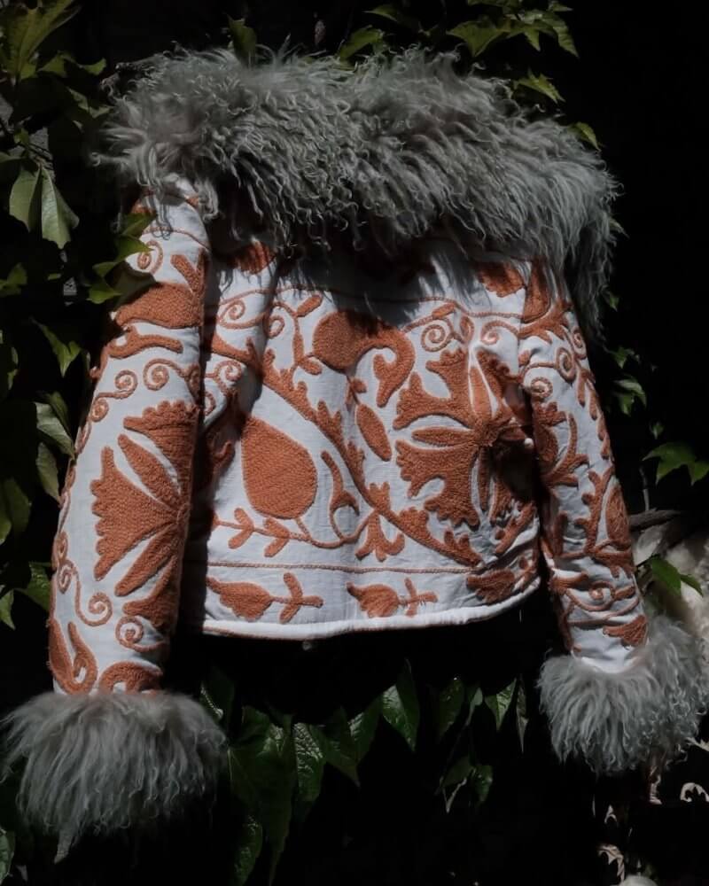 The Afghan Coat Martina No. 4 by Lunaré – back view flat lay outdoors, orange and cream floral embroidered coat with grey shaggy shearling collar and cuffs.