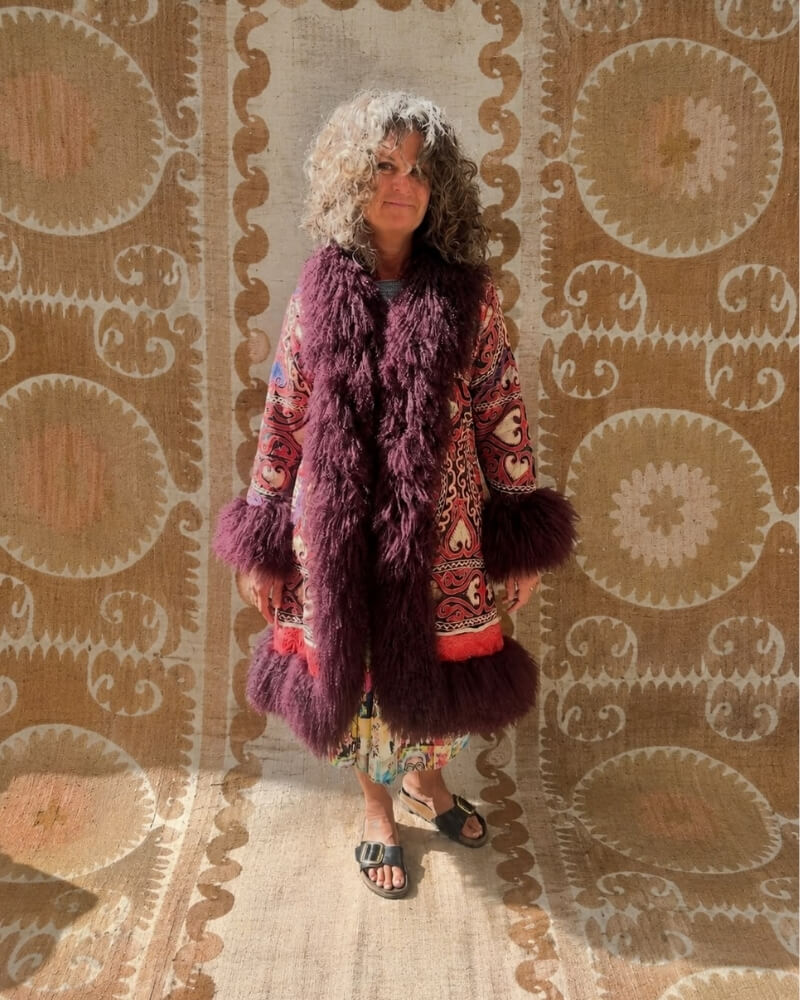 The Afghan Coat Ragna No. 4 by Lunaré – lifestyle shot on model, multicolor embroidered coat with plum shaggy shearling collar and cuffs.