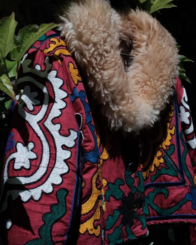 The Afghan Coat Coco No. 3 by Lunaré – detail shot outdoors, burgundy and green paisley patterned coat with cream shaggy shearling collar.