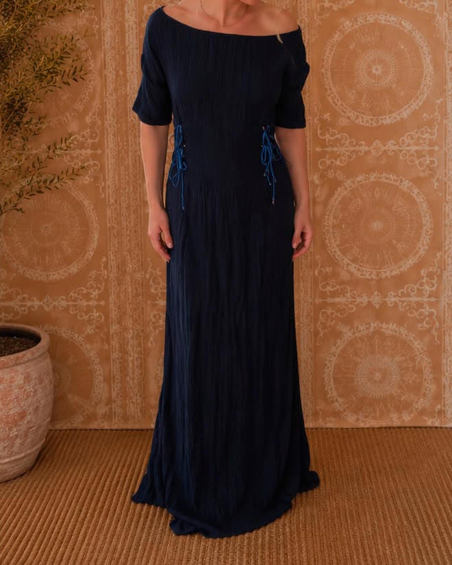 Woman wearing the Rose Dress in navy, sleeve version, front view showing the off-shoulder neckline, short sleeves and adjustable side lacing.