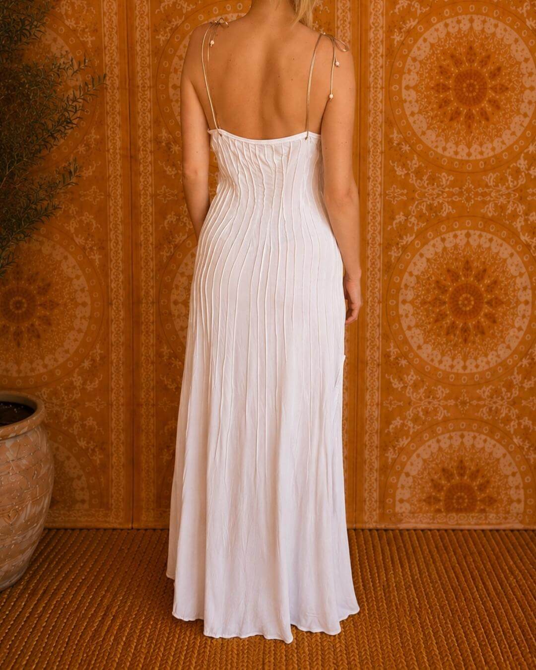 Woman modeling the Rose Dress in white, back view, showing the adjustable spaghetti straps and floor-length flowing skirt.